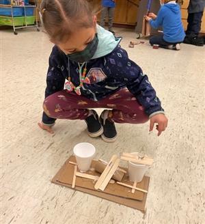 younger student creating a maze with cups and craft sticks